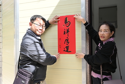 建築師與住戶一同將春聯張貼在電梯門口